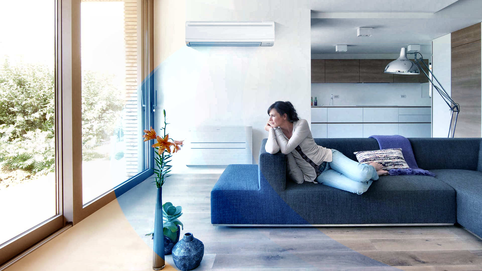 Vrouw relaxt comfortabel op een bank in een moderne woonkamer met een wandairco - sfeerbeeld van klimaatcomfort.